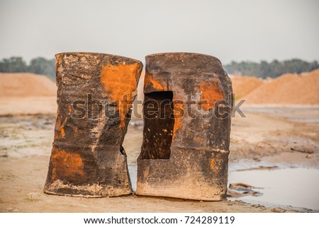 Close up of two rusted and brown colored broken oil drums at the beach