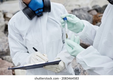 Close up of two scientists wearing hazmat suits collecting samples outdoors, toxic waste and pollution concept - Powered by Shutterstock