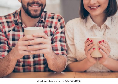 Close up of two smiling workers holding cups with tea.