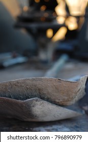 Close Up Of Two Stacked Scoop Shovels In Truck Bed At Construction Site, With Blurred Sunset In Background.