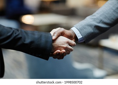 Close Up Of Two Successful Businessmen Shaking Hands In Office Building Lobby, Copy Space