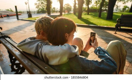 Close up of two women having fun, sitting on the bench in the city park. Lesbian couple taking selfie while spending time together outdoors. Homosexuality, LGBT and love. Selective focus. Web Banner