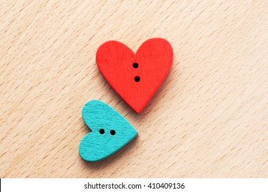 Close up of two wooden heart-shape buttons on the light wooden background - Powered by Shutterstock