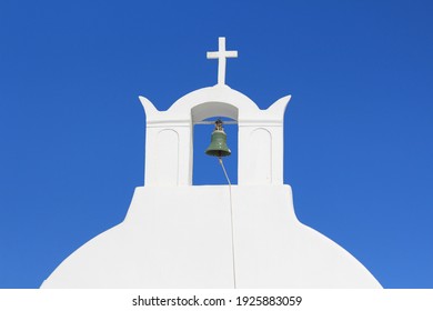 Close up of a typical Greek whitewashed bell tower with a cross on top. Blue sky in the background. Santorini, Greece - Powered by Shutterstock
