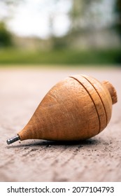 Close Up Of A Typical Wooden Spinning Top Laying On Concrete. Traditional Toys From Latin America. Quito's Festivities Concept. Nostalgic Games.