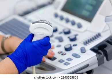 Close up of ultrasonography equipment, doctor hand in rubber gloves, holding ultrasound probe with coupling gel prepare for scanning. Special technology button for sonogram.