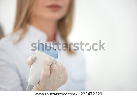 Close up of ultrasonography equipment, female doctor hand, wearing in rubber gloves, holding ultrasound probe with coupling gel prepare for scanning. Special technology button for sonogram.