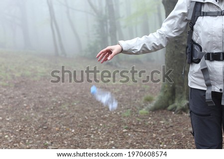 Close up of an uncivil trekker throwing garbage to the ground in nature