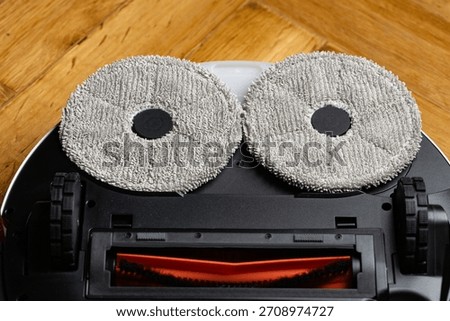 Close Up Underside of Robotic Mop Vacuum Cleaner Resembling a Minion or Smiley Face