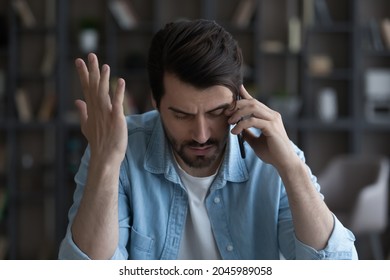 Close up unhappy businessman talking on smartphone, hearing bad news, unexpected debt or bankruptcy, financial problems, dismissal notification, frustrated upset young man making phone call