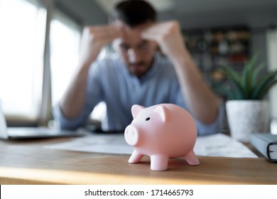 Close Up Unhappy Man Having Financial Problem, Frustrated Young Male Feeling Anxiety About Debt Or Bankruptcy, Financial Problem, Lack Of Money, Sitting At Work Desk With Pink Piggy Bank
