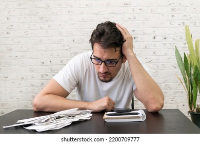 Close Up Of Unhappy Man Sitting At The Table, Stressed And Confused By Calculate Expense From Invoice Or Bills, Have No Money To Pay Mortgage Or Loan. High Prices And Spending Money Concept