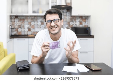 Close up of unhappy man sitting at the table, stressed and confused by calculate expense from invoice or bills, have no money to pay mortgage or loan. High prices and spending money concept