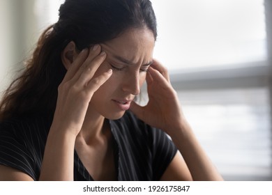 Close Up Unhappy Upset Woman With Closed Eyes Touching Temples, Suffering From Strong Tension Headache, Chronic Migraine, Breathing Deep, Tired Young Female Feeling Pain, Unwell And Unhealthy