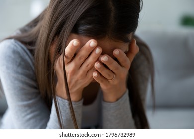 Close up unhappy young woman hiding face in hands, feeling desperate cheated hopeless alone indoors. Upset millennial girl crying, suffering from consequences of wrong decision, depression concept. - Shutterstock ID 1796732989