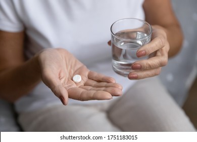 Close Up Of Unhealthy Elderly Woman Hold Pill And Glass Of Water Feeling Unwell Sick At Home, Ill Mature Female Take Antibiotic Aspirin Drug, Have Headache Or Migraine, Healthcare, Medicine Concept