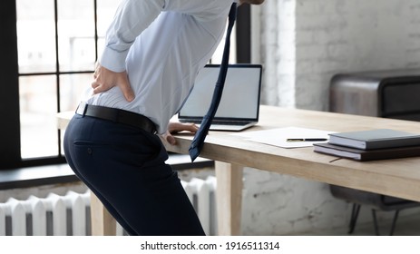 Close Up Of Unhealthy Male Employee Stand From Desk Sit In Incorrect Posture Suffer From Muscular Strain Or Spasm. Unwell Man Worker Struggle From Backache Or Pain In Office. Sedentary Life Concept.