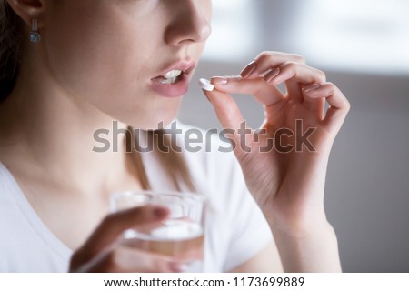 Close up of unhealthy woman feel unwell taking pill from headache or pain, female have painkiller or antibiotic medicine, girl hold glass of water and antidepressant suffering from depression