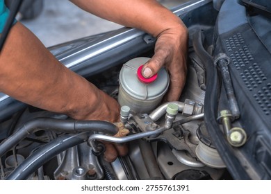 Close up unknown auto mechanic installing power steering pump in auto repair shop