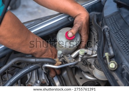 Close up unknown auto mechanic installing power steering pump in auto repair shop