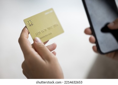 Close up unknown female hands holding modern smartphone and credit card, paying for goods or services, making instant money transfer remotely use mobile application, spend funds on-line, do e-shopping