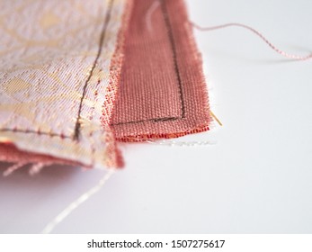 Close Up Of Unravel Pink-orange Linen Fabric Texture With Brown Thread Stitches With Copy Space. Materials, Textiles And Garment Concept.