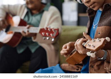 Close up of unrecognizable African American girl playing ukulele during music class indoors copy space - Powered by Shutterstock