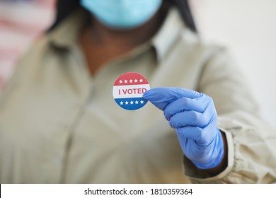 Close up of unrecognizable African-American woman holding I VOTED sticker while standing at polling station on post-pandemic election day, copy space
