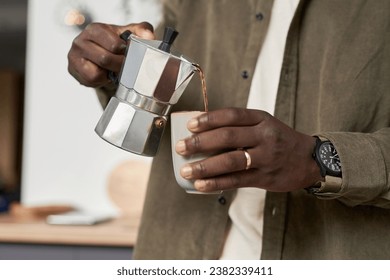 Close up of unrecognizable Black man making cup of delicious coffee at home and pouring drink into cup, copy space - Powered by Shutterstock