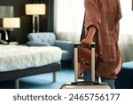 Close up of unrecognizable Black woman entering hotel room and holding suitcase upon travelling to resort copy space