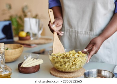 Close up of unrecognizable black woman mixing pasta in bowl while cooking in cozy kitchen, copy space - Powered by Shutterstock