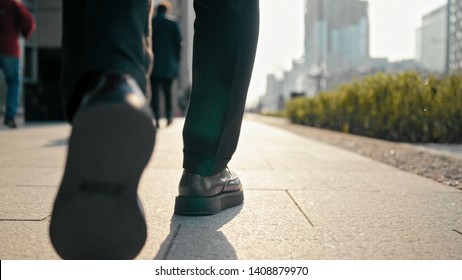 Close Up Unrecognizable Business Man Legs In Suit And Shoes Walking Outdoors In The Center Of Big City With Blurred Pedestrians In Busy Street In Spring Sunny Day