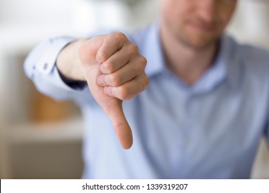 Close up of unrecognizable businessman with dissatisfied face showing negative sign, dislike with thumbs down, rejection concept at workplace, sign no, not approved, unhappy customer