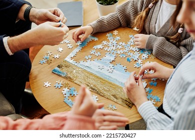 Close up of unrecognizable family playing jigsaw puzzle game together at home