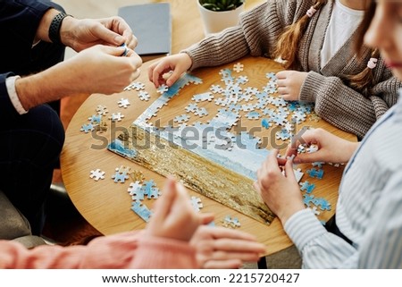 Close up of unrecognizable family playing jigsaw puzzle game together at home