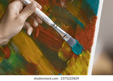 Close up unrecognizable female hand holding paintbrush, makes brush strokes on canvas painting abstract colorful pictures on easel. Professional artist prepare artwork, creative hobby, self-expression - Powered by Shutterstock