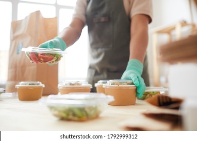 Close Up Of Unrecognizable Female Worker Wearing Protective Gloves While Packaging Orders At Food Delivery Service, Copy Space