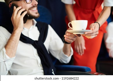 Close Up Of Unrecognizable Flight Attendant Serving Cup Of Coffee To Handsome Man Sitting In First Class And Enjoying Flight, Copy Space