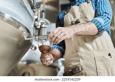 Close up of unrecognizable male brewmaster pouring glass of beer at brewing factory - Powered by Shutterstock