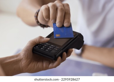 Close up Unrecognizable male customer pay by contactless credit card with NFC tech. Waitress hand hold card reader machine serving to public place client, sell commercial services. Electronic money
