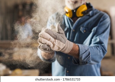 Close up of an unrecognizable male hands with work gloves on, clapping to remove sawdust - Powered by Shutterstock