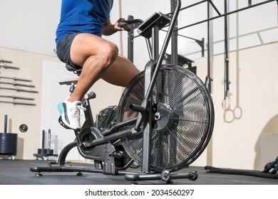 Close up of an unrecognizable man doing cardio training on stationary air bike machine with fan at the gym. High quality photo - Shutterstock ID 2034560297