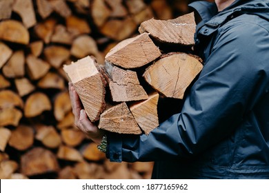 Close up of unrecognizable man dressed in jacket carries bundle of firewood, going to make fire outdoor. Winter is coming. - Powered by Shutterstock