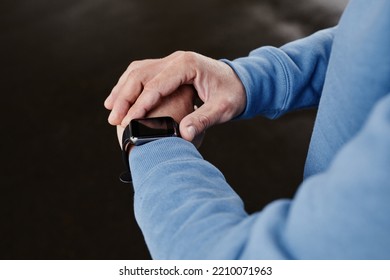 Close up of unrecognizable man setting up smartwatch against black background, copy space - Powered by Shutterstock