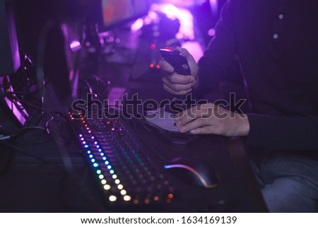 Close up of unrecognizable man using racing joystick while playing video games in dark room, copy space