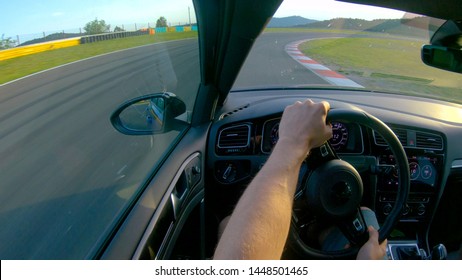 CLOSE UP Unrecognizable Race Car Driver Speeding Along Empty Track On Sunny Day. Young Man Enjoying A Sunny Day By Driving His Sportscar Along The Closed Track. Adrenaline Junkie Racing In A Fast Car