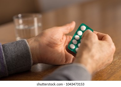 Close up of unrecognizable senior person taking aspirin with glass of water