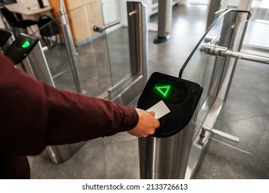 Close up of unrecognizable swiping card passing turnstile to enter building. The hand holds the card. Access is allowed. - Shutterstock ID 2133726613