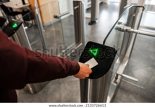 Close up of unrecognizable swiping card passing\
turnstile to enter building. The hand holds the card. Access is\
allowed.
