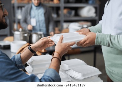 Close up of unrecognizable volunteer giving hot meal in takeaway box to refugees in help center, copy space - Powered by Shutterstock